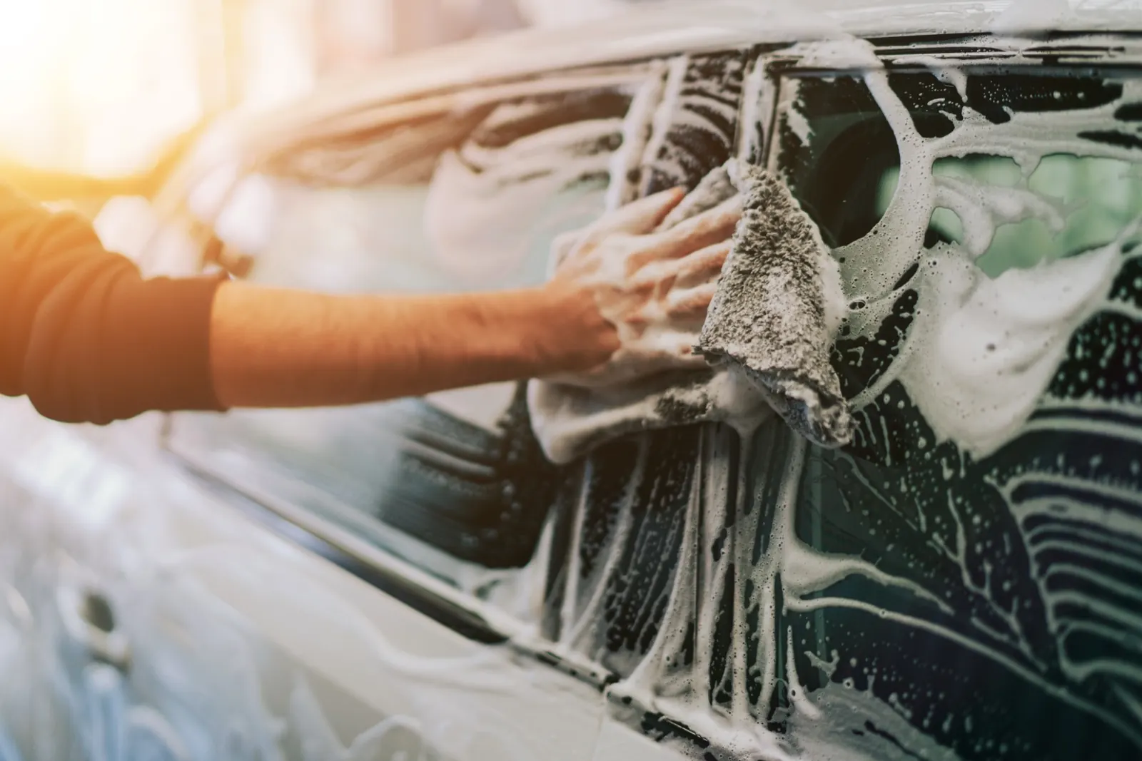Schonende Handwäsche eines Autos mit Waschhandschuh und Reinigungsschaum